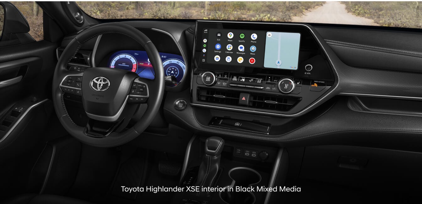 Toyota Highlander Hybrid LE in Black Fabric with touchscreen display facing dirt trail.