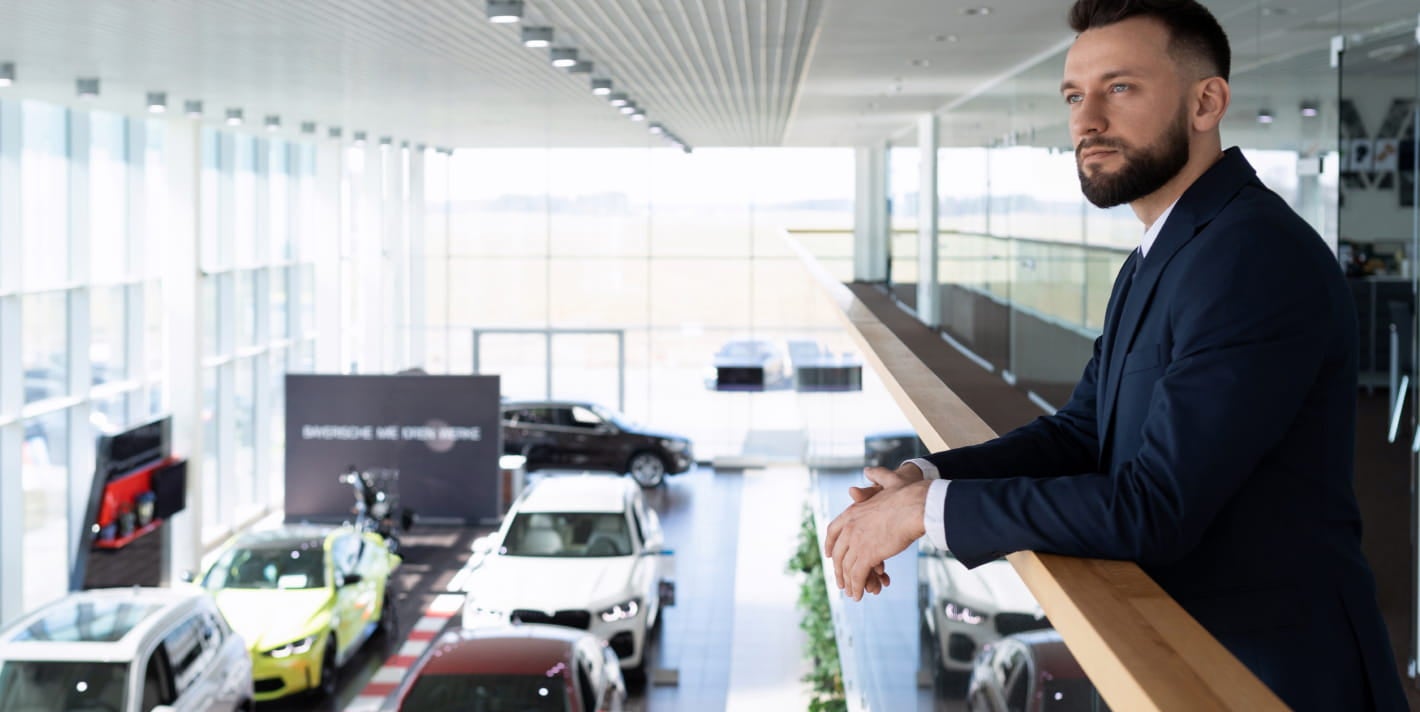 Car dealership representative overlooking a modern showroom with multiple vehicles on display.