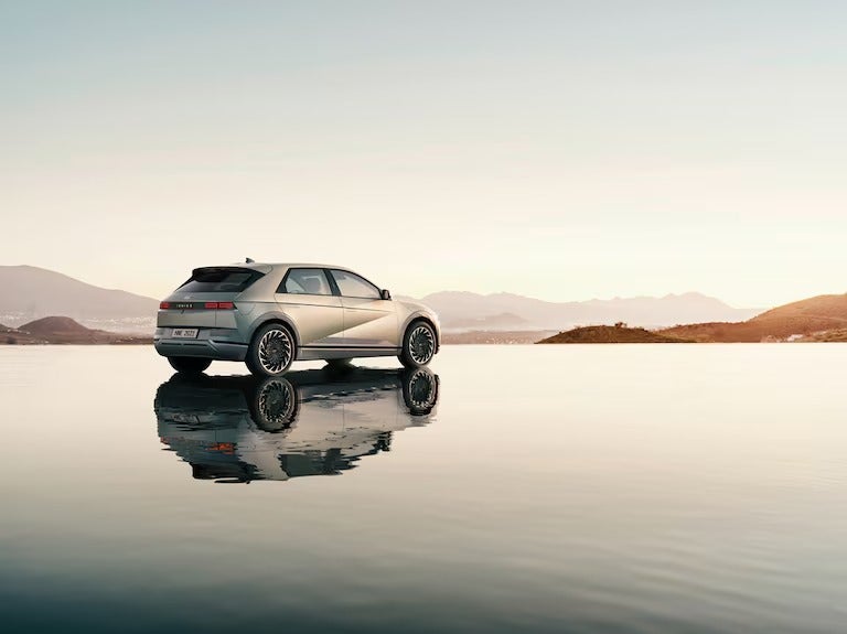 Backside three quarter view of the Hyundai Ioniq5 serenely sitting on top of highly reflective shallow water pool