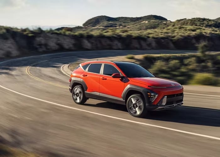 Hyundai Kona rounding a soft turn on a desert road.