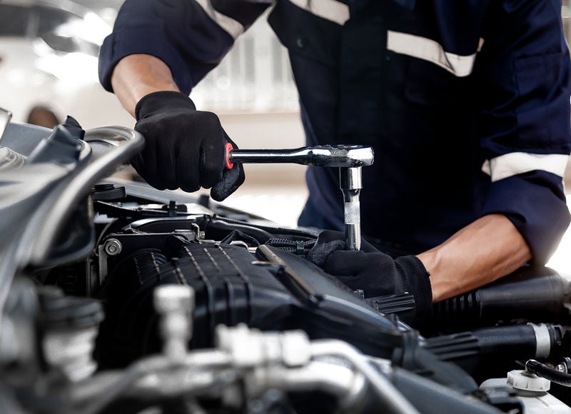 A close-up view of a person working inside a vehicle's engine compartment